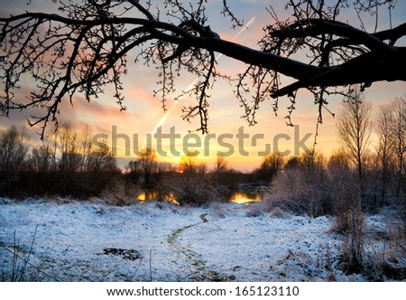 Winter landscape with sun and frozen river. Sunset.