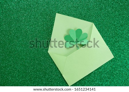 St. Patrick's day, pattern of clovers cut out of paper on a green shiny background