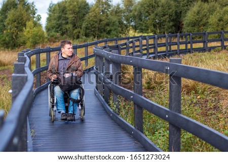 Wheelchair user on accessible path Royalty-Free Stock Photo #1651273024