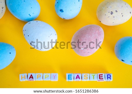Easter greeting card with painted eggs. Seasonal Easter message "Happy easter". Pastel and colorful decorated easter eggs with greeting card with text on yellow background. Spring holidays concept.