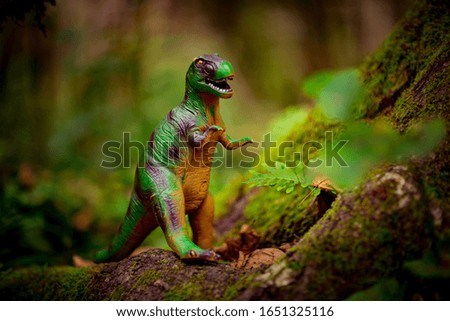 toy dinosaur, standing near a green tree in the forest, in the summer