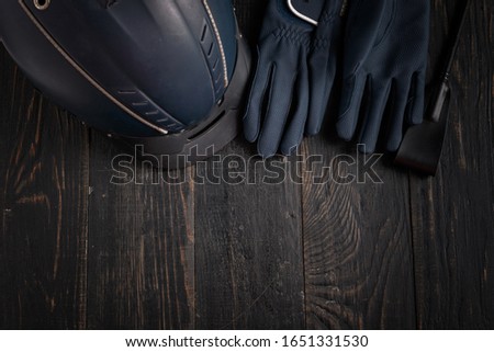 Items of equipment of horse jockey, jockey. Helmet, gloves, whip on black table