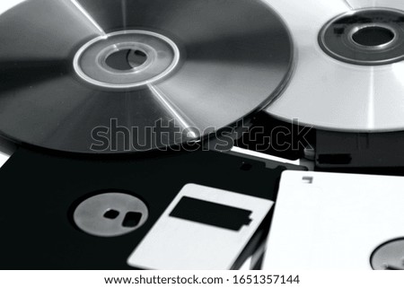 Retro Computering data media storage. Compact disc and three inch and a half floppy disks. Black and white photo