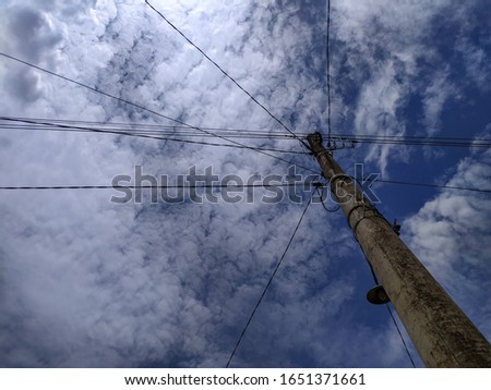 Photo of electric poles, blue sky and white clouds.