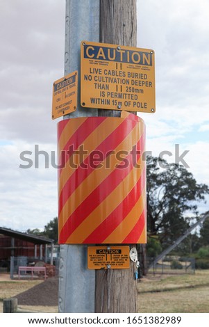 yellow/black and yellow/red caution and hazard signs warning of live electricity cables underground