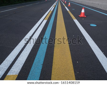 Various lines painted on asphalt. Yellow, blue, white. Part of a training ground for drivers.