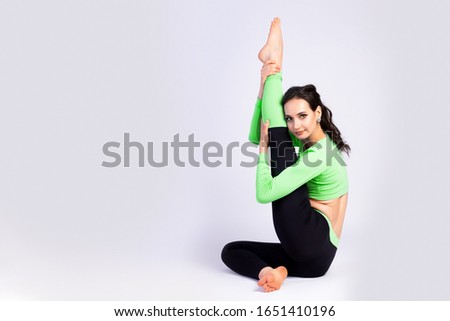 Beautiful  woman gymnast in a tight fit tights stretch and smiling on a bright white isolated background. The concept of gymnasts and sports stretching, oriental relaxation practices