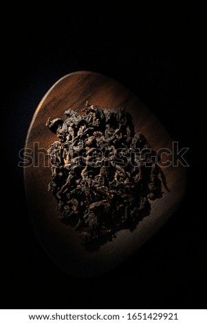 Some tea leaves are in a walnut plate.  Tea leaves closeup.