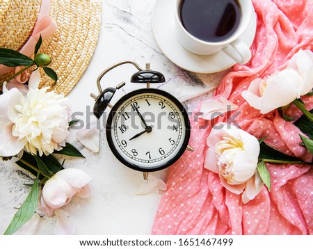 Good morning. Tea, alarm clock and bouquet of white peony on marble background. Flat lay. Top view. Copy space.