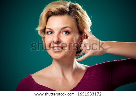 Woman with short blond hair showing call phone gesture. People,lifestyle and communications concept