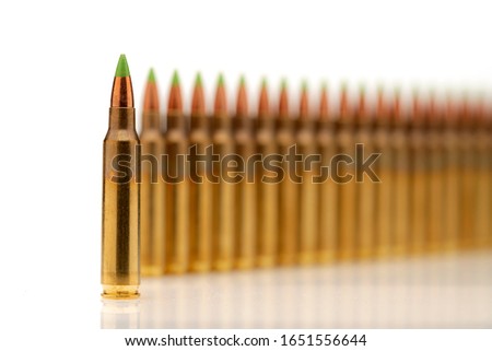 A group of 5.56 calibar, green tip bullets ordered into the line on white background