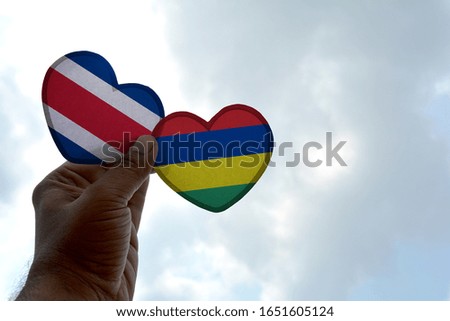 Hand holds a heart Shape Costa Rica and Mauritius flag, love between two countries