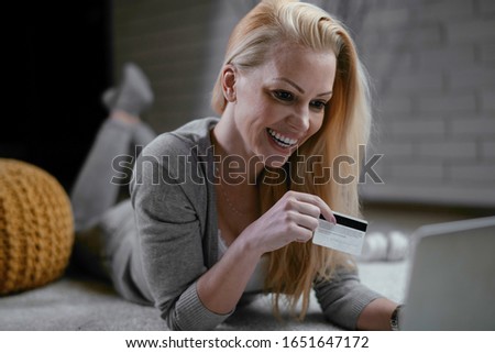 Woman buying online. Beautiful woman lying on floor with laptop and credit card. 