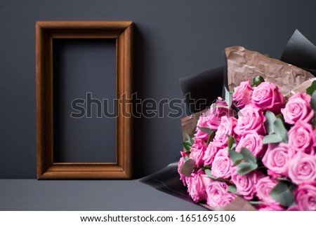 Flower arrangement. Pink flowers, wooden photo frame on pastel gray background, copy space