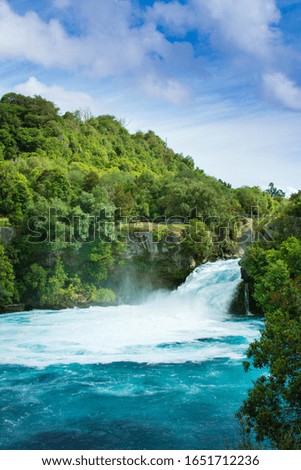 Magnificent Huka Falls and the pool beneath amongst lush green trees covered rocks. Taupo, New Zealand