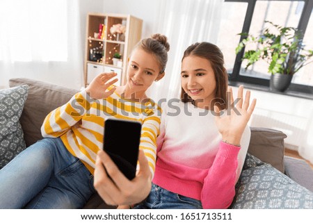 people, technology and friendship concept - happy teenage girls taking selfie with smartphone or having video chat at home Royalty-Free Stock Photo #1651713511