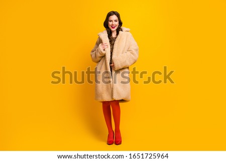 Full length body size view of nice attractive lovely charming fashionable cheerful wavy-haired girl wearing soft comfortable fur coat isolated on bright vivid shine vibrant yellow color background