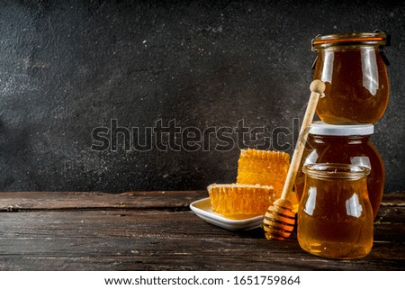 Autumn harvest. Organic farm honey in jars with honeycombs. Beekeeping products. On a wooden rustic background