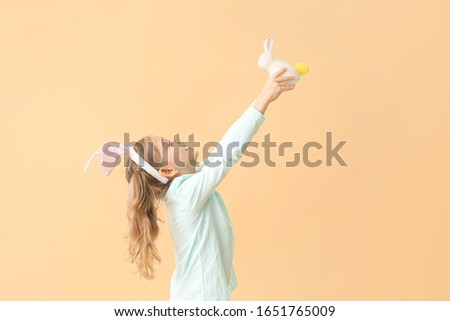 Little girl with Easter bunny on color background