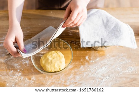 top view of woman covering dough in bowl with towel