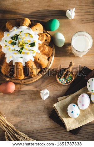 top view of easter cake near glass of milk, figurines with rabbits and painted eggs