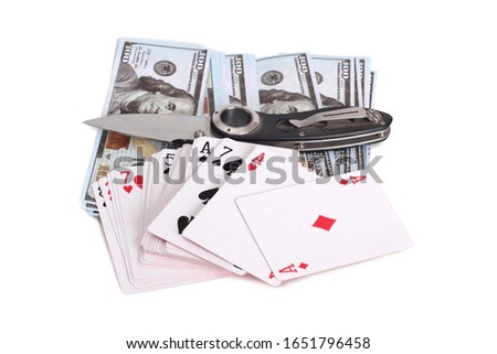 Folding knife and playing cards lie on paper dollars. Isolated objects on a white background