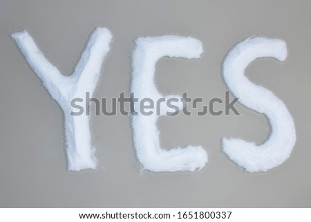 Inscription with white grains on a gray background. Text is "YES".