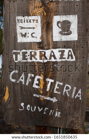 wooden tourist sign pointing out to the direction of the mountain lookout, toilet and cafe catering terrace, written in Spanish Terraza