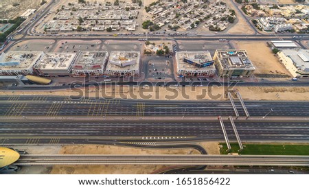 Aerial top view of Sheikh Zayed highway road timelapse in Dubai with traffic, toll gate and a metro station. Some shops and houses near this road.
