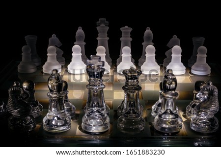 Dark and mysterious chessboard made of glass, with pieces in frosted and clear glass