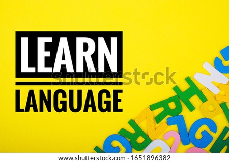 LEARN LANGUAGE text with ABC wooden letters alphabet scattered on a yellow background. Education and copy space  