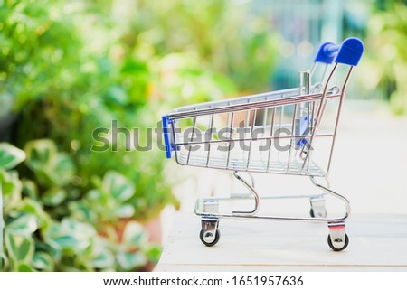 Empty miniature shopping cart on green natural outdoor garden in concept of go green or no plastic bag Royalty-Free Stock Photo #1651957636