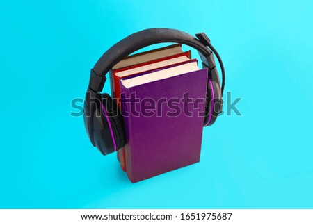 Audio book concept with headphones and stack of books on blue background. E-learning. Listening to a book. 