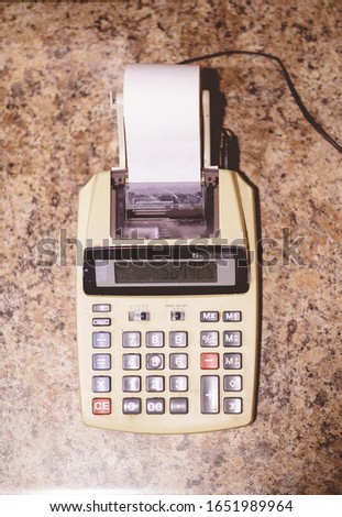A closeup shot of a desktop calculator with a paper tape