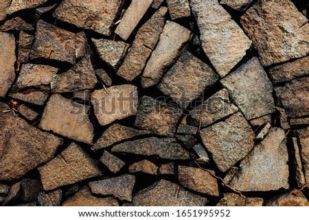 Natural, brown stone of different sizes, randomly placed. The texture of the stone wall. Stone wall of arbitrary size. Background of stone wall. Natural materials