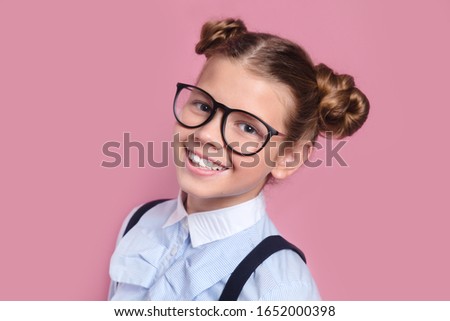 Close-up portrait of a young girl with glasses looking at camera