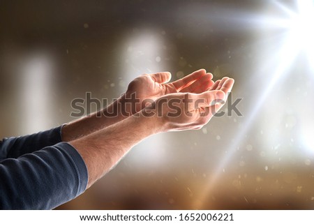hands together with palms up in a church with sparkles and ray of light. Horizontal composition