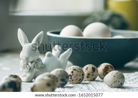 Composition of eggs on a gray background, ceramic figurine of an Easter rabbit