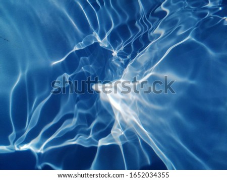 The​ abstract​ of surface​ blue​ water​ in​ the​ deep​ sea​ for blue background. Blue​ water​ splash​ed​ in​ the​ deep sea for​ background​
