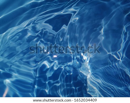 The​ abstract​ of surface​ blue​ water​ in​ the​ deep​ sea​ for blue background. Blue​ water​ splash​ed​ in​ the​ deep sea for​ background​