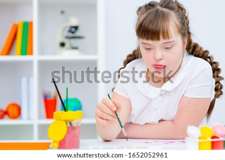 Girl with Down Syndrome draws at home