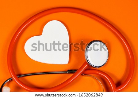 wooden heart and stethoscope on an orange background