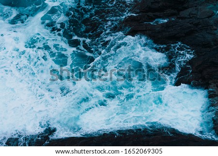 White sea foam produced when the waves collide with the rocks of the coast