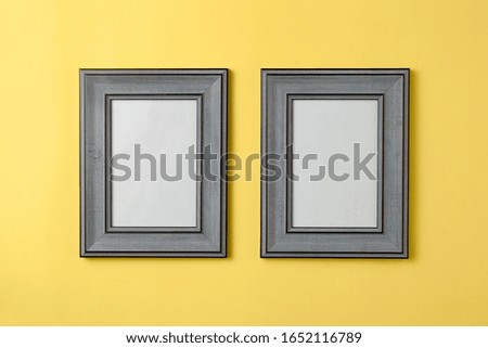 Two blank grey wooden photo frame on yellow background