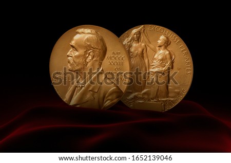 Nobel Prize Medal standing on a platform. Red and black background. Royalty-Free Stock Photo #1652139046