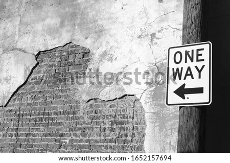 One-way sign next to old brick wall - black-and-white