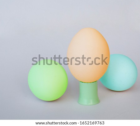 
Three easter eggs in green, orange and blue on a light gray background