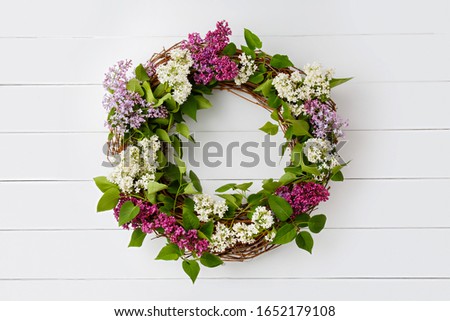 Wreath from purple lilac flowers on white wooden background. Surprise for lovely woman. Natural spring style. Aromatherapy.  Flowers Flat lay, top view. Background with copy space. Spring blossom mood Royalty-Free Stock Photo #1652179108
