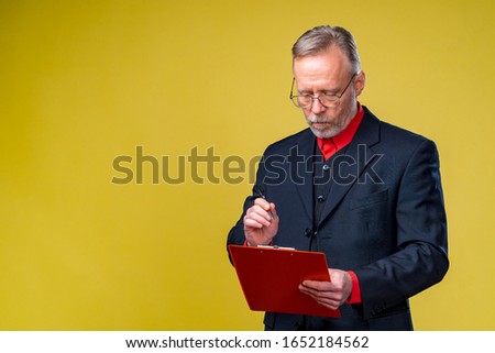 Middle aged businessman standing and holding file folder. Horizontal format isolated on yellow background.