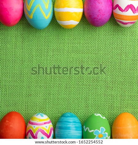 Easter Eggs, bright and colorful, in a Row on Green Burlap Background.  It's a square photo with flat layout